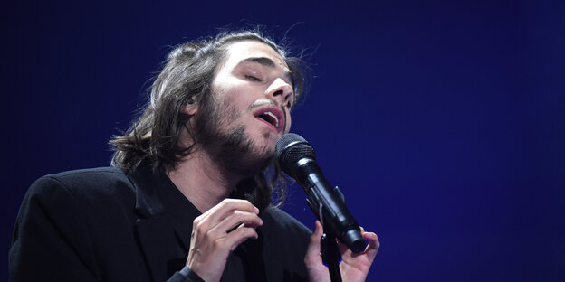 Der Sänger Salvador Sobral singt vor dunklem Hintergrund Der Sänger Salvador Sobral singt vor dunklem Hintergrund