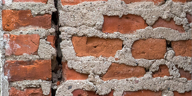 Eine Backsteinmauer mit einem Riss Eine Backsteinmauer mit einem Riss