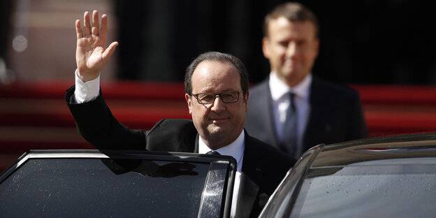 Francois Hollande steht winkend hinter einer Autotür. Unscharf dahinter sieht man Emmanuel Macron Francois Hollande steht winkend hinter einer Autotür. Unscharf dahinter sieht man Emmanuel Macron