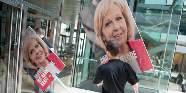 Menschen tragen Plakate mit dem Konterfei Hannelore Krafts durch eine Tür Menschen tragen Plakate mit dem Konterfei Hannelore Krafts durch eine Tür