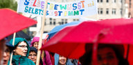 Frauen tragen Kapuzen und Regenschirme sowie ein Transparent mit den Worten "Selbstbewusst und selbtsbestimmt" durch die Hamburger Innenstadt.