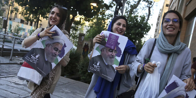 Iranische Frauen in grünen und violetten Gewändern breiten beide Arme aus und jubeln Iranische Frauen in grünen und violetten Gewändern breiten beide Arme aus und jubeln