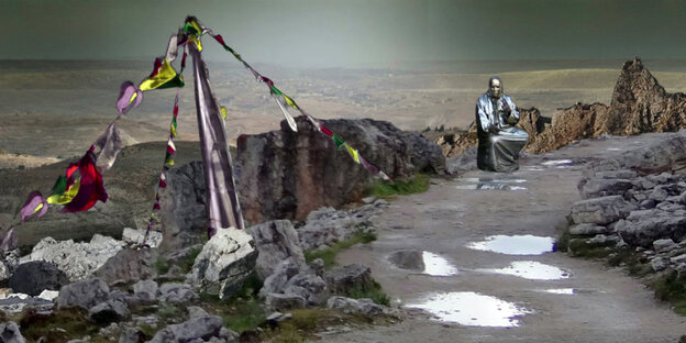 Eine karge, nasse, graue Landschaft, da sitzt eine Figur mit Maske. Eine karge, nasse, graue Landschaft, da sitzt eine Figur mit Maske.