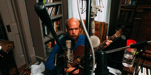 Bonnie „Prince“ Billy sitzt hinter Mikrofonen und spielt Guitarre Bonnie „Prince“ Billy sitzt hinter Mikrofonen und spielt Guitarre