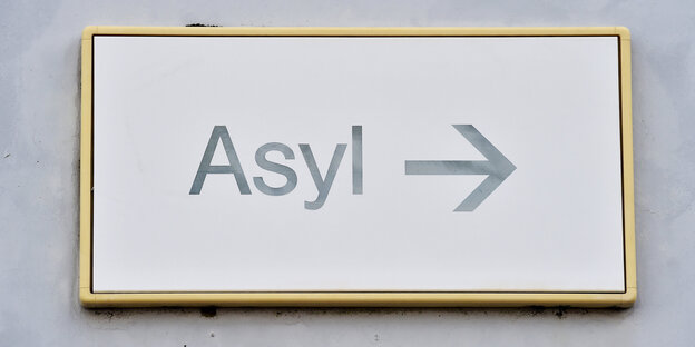 Auf einem Schild an einer Wand steht „Asyl“ mit einem Pfeil Auf einem Schild an einer Wand steht „Asyl“ mit einem Pfeil