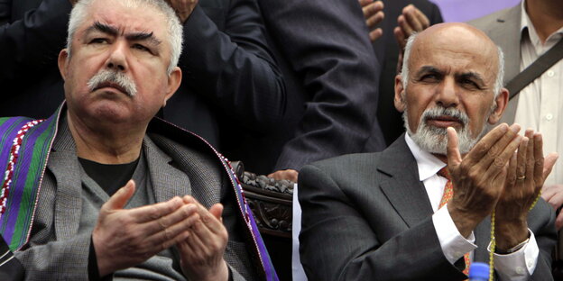 Raschid Dostum und Aschraf Ghani sitzen nebeneinander und haben die Hände zum Gebet erhoben Raschid Dostum und Aschraf Ghani sitzen nebeneinander und haben die Hände zum Gebet erhoben
