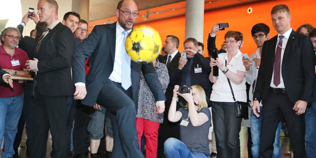Martin Schulz kickt einen gelben Fußball mit dem Knie in die Luft Martin Schulz kickt einen gelben Fußball mit dem Knie in die Luft
