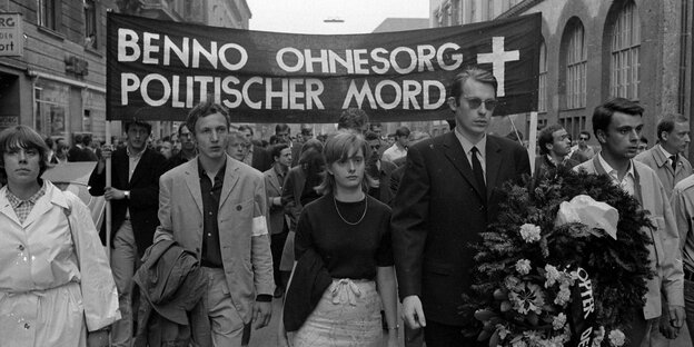 Menschen auf einer Demonstration. Auf dem Transparent steht: Benno Ohnesorg Politischer Mord. Schwarz Weiß