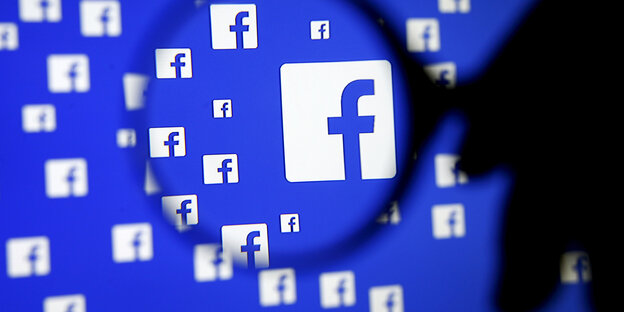 Eine Hand mit einer Lupe vor vielen Facebook-Logos Eine Hand mit einer Lupe vor vielen Facebook-Logos
