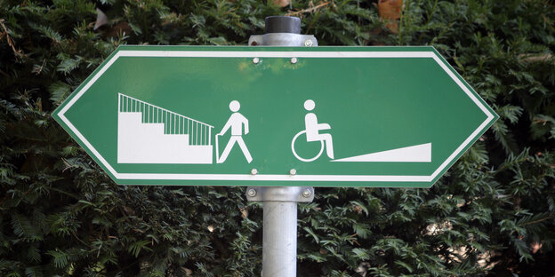 Ein Schild zeigt in zwei Richtungen, rechts ist eine Rampe für Rollstuhlfahrer, links eine Treppe für Fußgänger Ein Schild zeigt in zwei Richtungen, rechts ist eine Rampe für Rollstuhlfahrer, links eine Treppe für Fußgänger