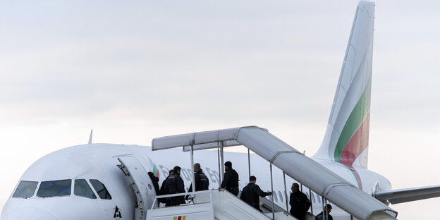 Menschen gehen über eine offene Gangway in ein Flugzeug Menschen gehen über eine offene Gangway in ein Flugzeug
