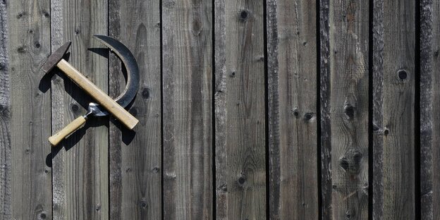 Ein Hammer und eine Sichel hängen an einer Holzwand Ein Hammer und eine Sichel hängen an einer Holzwand