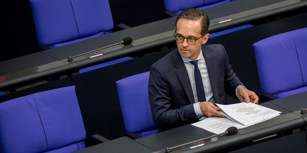 Ein Mann sitzt im Parlament und blättert durch Unterlagen Ein Mann sitzt im Parlament und blättert durch Unterlagen