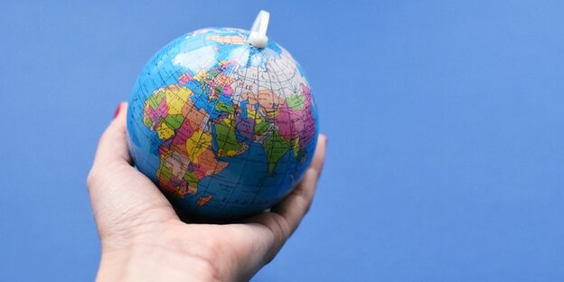 Eine Hand hält einen Mini-Globus Eine Hand hält einen Mini-Globus