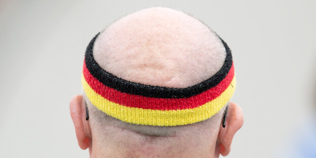 Ein Mann mit Glatze und Stirnband in schwarz-rot-gold ist von hinten zu sehen Ein Mann mit Glatze und Stirnband in schwarz-rot-gold ist von hinten zu sehen