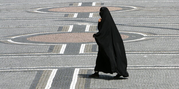 Frau im Nikab läuft über einen sonnigen Platz