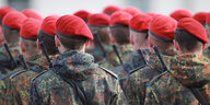 Soldaten mit roten Barrets stehen mit dem Rücken zum Betrachter in Reih und Glied