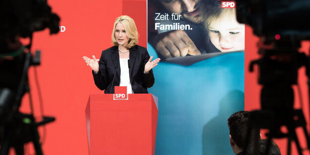 Eine Frau spricht vor Publikum und Kameras Eine Frau spricht vor Publikum und Kameras