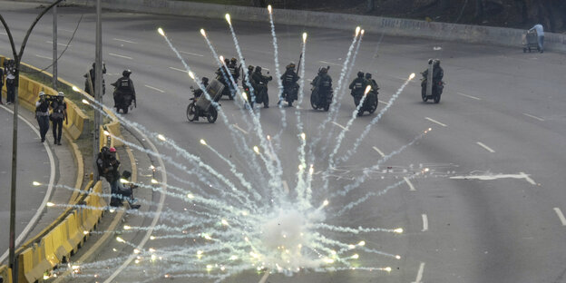 Ein Feuerwerk auf einer Straße, dahinter Polizeikräfte Ein Feuerwerk auf einer Straße, dahinter Polizeikräfte