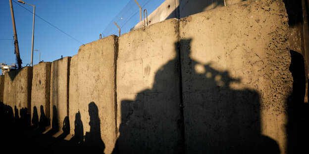 eine Mauer, darauf der Schatten eines Bewaffneten eine Mauer, darauf der Schatten eines Bewaffneten