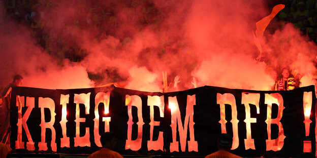 Im Hintergrund roter Rauch und Flammen, im Vordergrund der Schriftzug "Krieg dem DFB" Im Hintergrund roter Rauch und Flammen, im Vordergrund der Schriftzug "Krieg dem DFB"