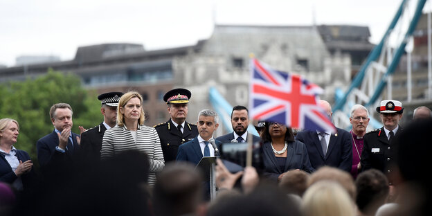Auf einer Bühne steht Londons Bürgermeister und spricht. Vor ihm stehen viele Menschen, eine britische Flagge ist deutlich zu sehen. Auf einer Bühne steht Londons Bürgermeister und spricht. Vor ihm stehen viele Menschen, eine britische Flagge ist deutlich zu sehen.