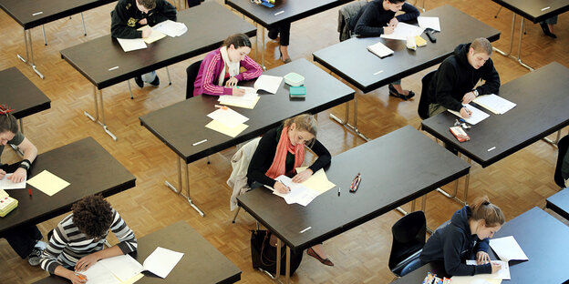 Schüler sitzen an Tischen, vertieft ins Schreiben und Lesen.