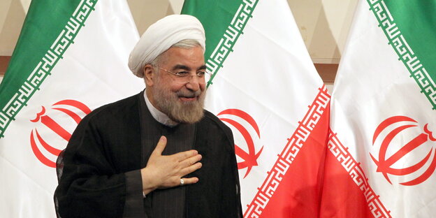 Der iranische Präsident Hassan Ruhani tritt vor die Presse; im Hintergrund sieht man iranische Flaggen Der iranische Präsident Hassan Ruhani tritt vor die Presse; im Hintergrund sieht man iranische Flaggen