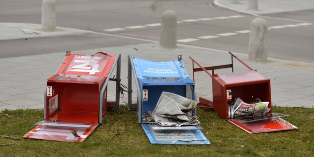 Am Straßenrand liegen drei Kästen, aus denen man sich Zeitungen nehmen kann. Am Straßenrand liegen drei Kästen, aus denen man sich Zeitungen nehmen kann.