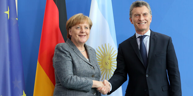 Ein Mann und eine Frau schütteln sich die Hände, im Hintergrund, die europäische und die argentinische Flagge Ein Mann und eine Frau schütteln sich die Hände, im Hintergrund, die europäische und die argentinische Flagge