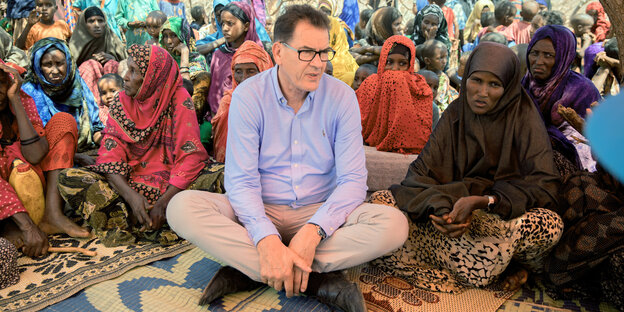 Gerd Müller sitzt im Schneidersitz zwischen Somalieriennen Gerd Müller sitzt im Schneidersitz zwischen Somalieriennen