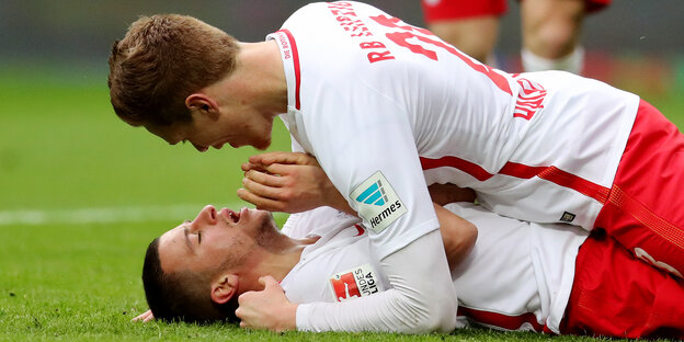 Zwei Fußballer liegen erschöpft aufeinander Zwei Fußballer liegen erschöpft aufeinander