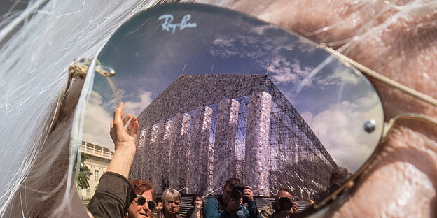 Im Glas einer verspiegelten Sonnenbrille spiegelt sich ein Tempel aus Büchern Im Glas einer verspiegelten Sonnenbrille spiegelt sich ein Tempel aus Büchern