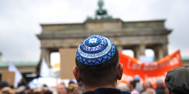 Ein Mann mit einer Kippa von hinten, im Hintergrund das Brandenburger Tor Ein Mann mit einer Kippa von hinten, im Hintergrund das Brandenburger Tor