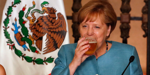 Angela Merkel hebt ein Glas Bier zum Mund. Angela Merkel hebt ein Glas Bier zum Mund.