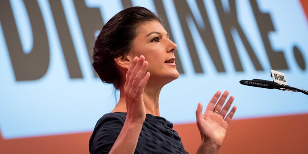 Sarah Wagenknecht mit ausgebreiteten Armen an einem Rednerpult Sarah Wagenknecht mit ausgebreiteten Armen an einem Rednerpult
