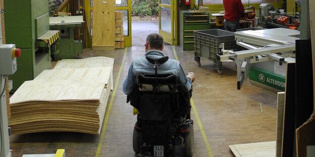 Ein Mann fährt im Rollstuhl auf eine Tür zu Ein Mann fährt im Rollstuhl auf eine Tür zu