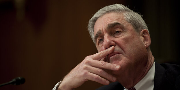 Robert Mueller sitzt vor schwarzem Hintergrund, guckt sinnierend in die Luft und hat den Kopf auf seine rechte Hand gestützt Robert Mueller sitzt vor schwarzem Hintergrund, guckt sinnierend in die Luft und hat den Kopf auf seine rechte Hand gestützt