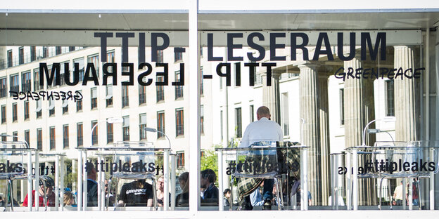 Ein Mann sitzt in einem gläsernen Raum mit der Aufschrift "TTIP-Leseraum" - "#ttipleaks" Ein Mann sitzt in einem gläsernen Raum mit der Aufschrift "TTIP-Leseraum" - "#ttipleaks"