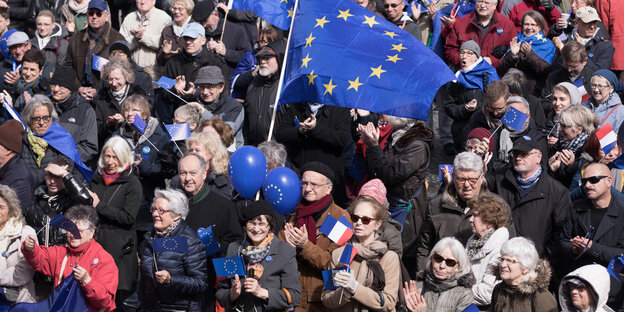 Viele dicht stehende Menschen, über ihnen die blaue Europafahne. Viele dicht stehende Menschen, über ihnen die blaue Europafahne.