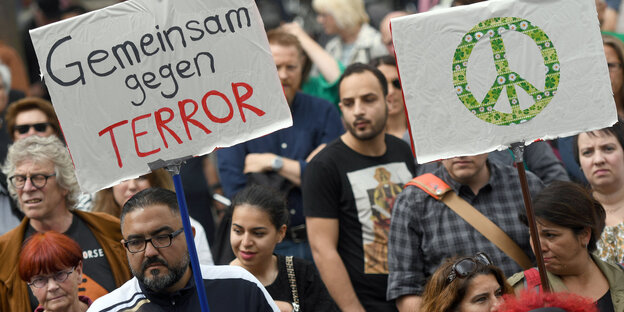 Menschen laufen auf einer Straße und halten Schilder hoch Menschen laufen auf einer Straße und halten Schilder hoch
