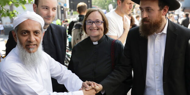 Ein Imam, ein Rabbi und eine Pfarrerin legen ihre Hände aufeinander Ein Imam, ein Rabbi und eine Pfarrerin legen ihre Hände aufeinander