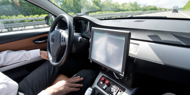 Ein Mensch in einem Auto, die Hände neben dem Lenkrad abgelegt Ein Mensch in einem Auto, die Hände neben dem Lenkrad abgelegt