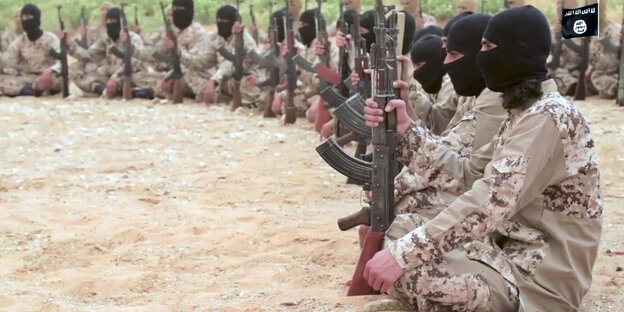 Kämpfer der Terrormiliz "Islamischer Staat" sitzen im Kreis, in der Hand halten sie Gewehre Kämpfer der Terrormiliz "Islamischer Staat" sitzen im Kreis, in der Hand halten sie Gewehre