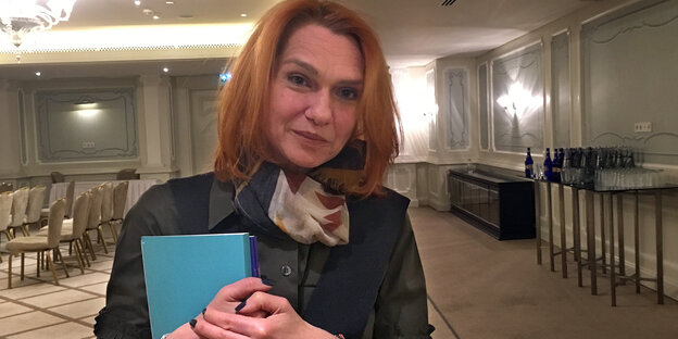 Asli Erdogan schaut lächelnd in die Kamera und hält eine blaue Mappe im Arm Asli Erdogan schaut lächelnd in die Kamera und hält eine blaue Mappe im Arm
