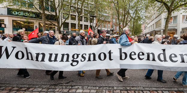 Demonstranten halten ein Schild hoch mit der Aufschrift: Wohnungsnot beenden Demonstranten halten ein Schild hoch mit der Aufschrift: Wohnungsnot beenden