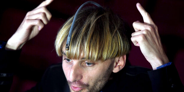 Der Cyborg Neil Harbisson zeigt auf eine Art Antenne auf seinem Kopf, mit der er Farben hören kann Der Cyborg Neil Harbisson zeigt auf eine Art Antenne auf seinem Kopf, mit der er Farben hören kann