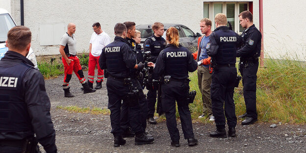 Uniformierte stehen vor einem Haus