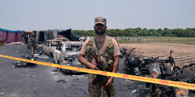 Ein pakistanischer Soldat steht an der Unfallstelle hinter gelbem Absperrband Ein pakistanischer Soldat steht an der Unfallstelle hinter gelbem Absperrband