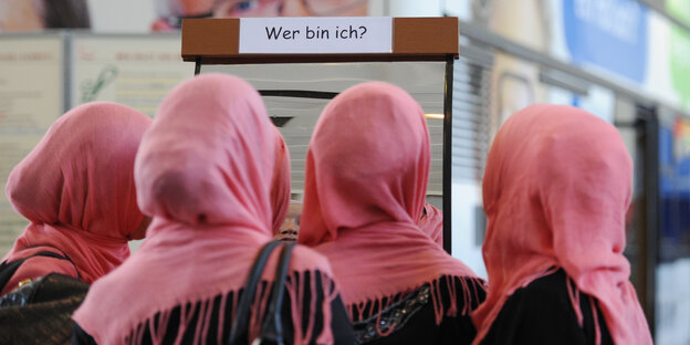 Vier junge Frauen von Hinten mit Kopftüchern in demselben Rosaton Vier junge Frauen von Hinten mit Kopftüchern in demselben Rosaton